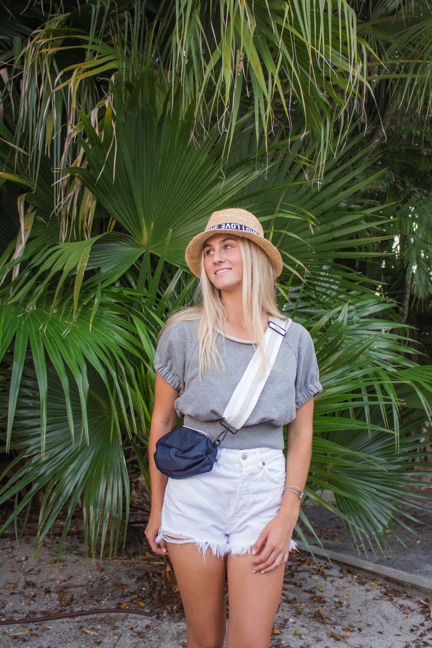 Person wearing navy nylon belt bag with white crossbody strap with white leather detail