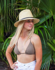 Person wearing a natural straw panama hat with thin brown leather band.