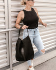 Person holding black sporty mesh tote bag with black leather and webbing details.