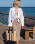 Person holding the Benicia straw tote bag with black leather handles and black & white center stripe.