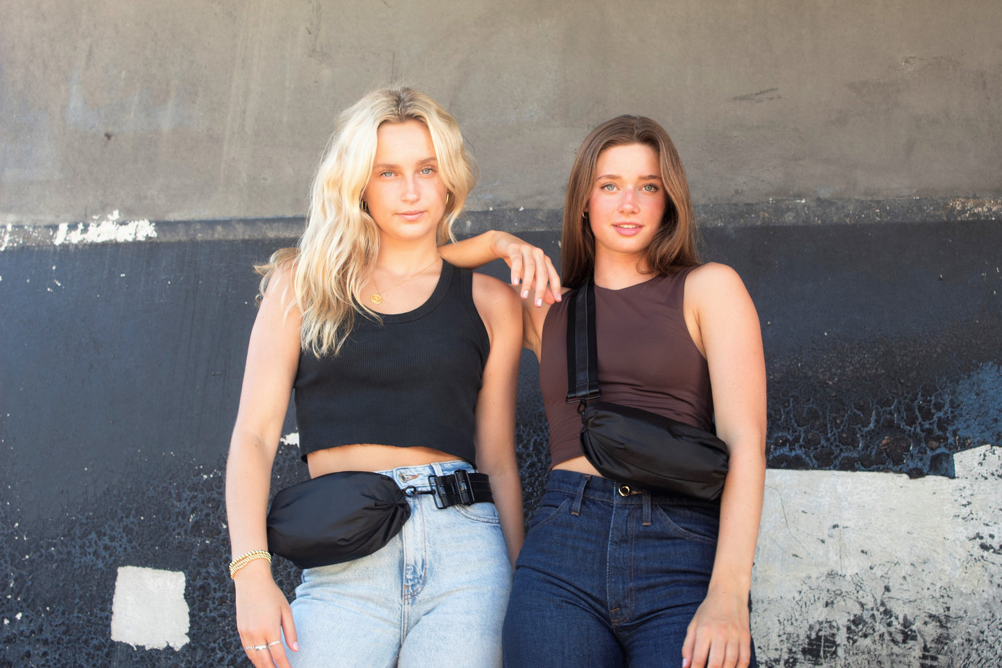 Two people wearing the Orlando Black Bags, one as a belt bag, one as a crossobdy