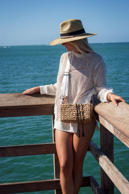 Person wearing the Hampton mini straw bag with white crossobdy strap with leather details and the Tower straw hat