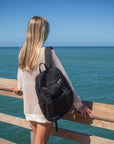 Person wearing the Anya & Niki Newberry backpack - a black mesh backpack with leather details and shiny silver drawstring top.