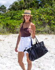 Person wearing natural colored crochet straw fedora hat with black & white stripe band.