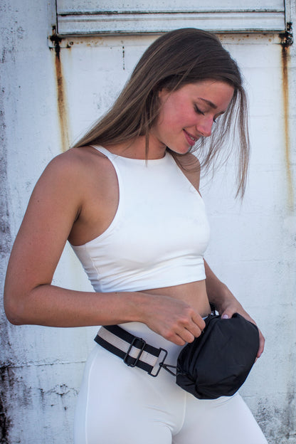 Person wearing black nylon belt bag with black crossbody strap with cream leather detail