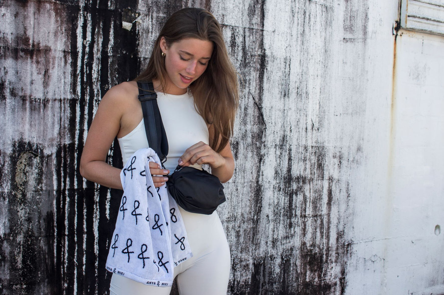 Person wearing black nylon belt bag with black crossbody strap with black leather detail