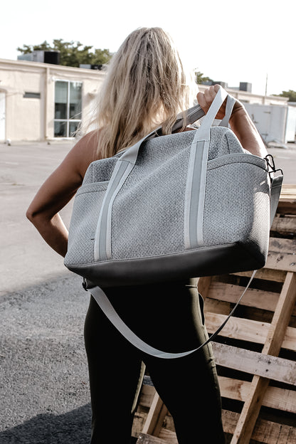 person holding the Callahan light gray perforated neoprene duffel bag  over their back
