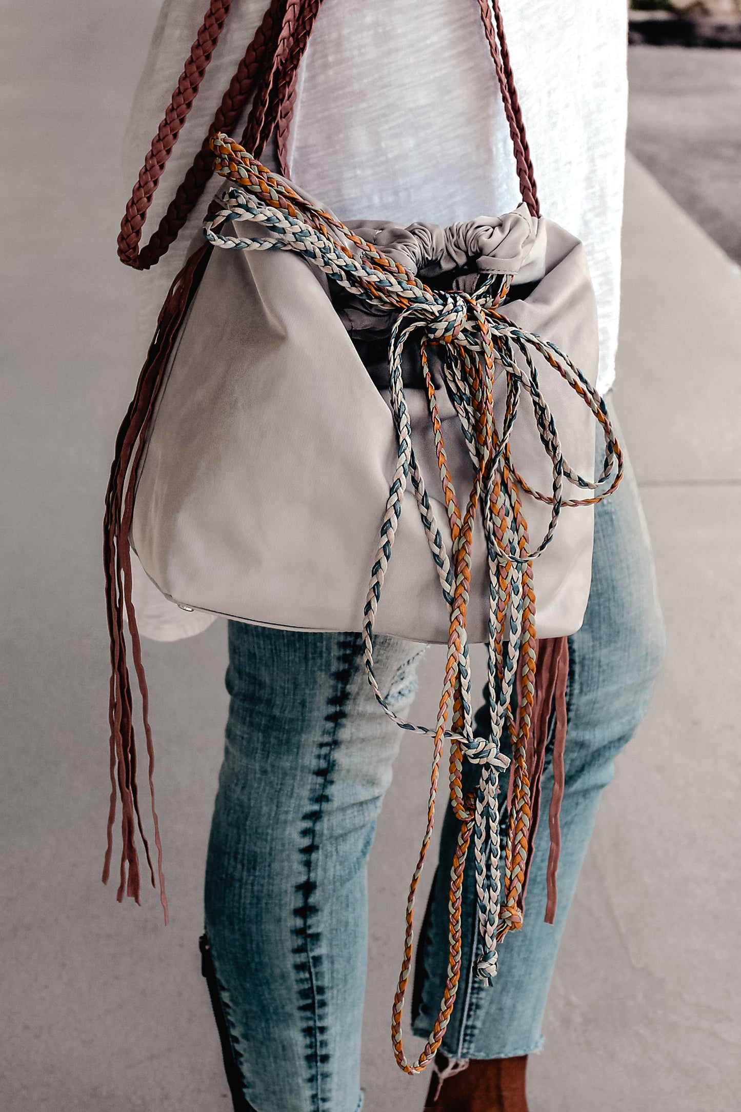 person wearing sporty gray nylon cinch bag with colorful braided leather straps.