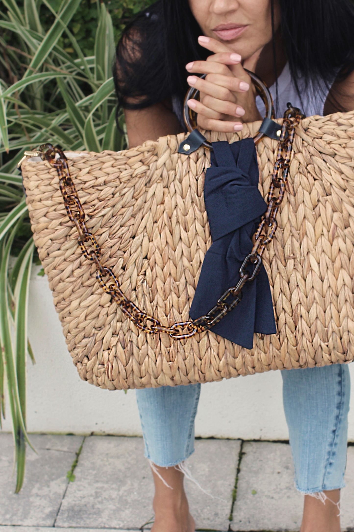 person holding extra-large hyacinth straw tote with torte and navy accents.