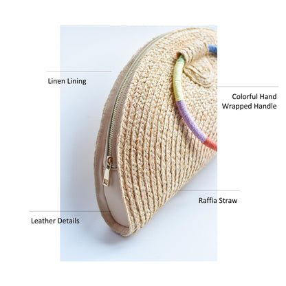 Natural raffia straw half-moon clutch with rainbow colored wrapped circle handle and leather sides.
