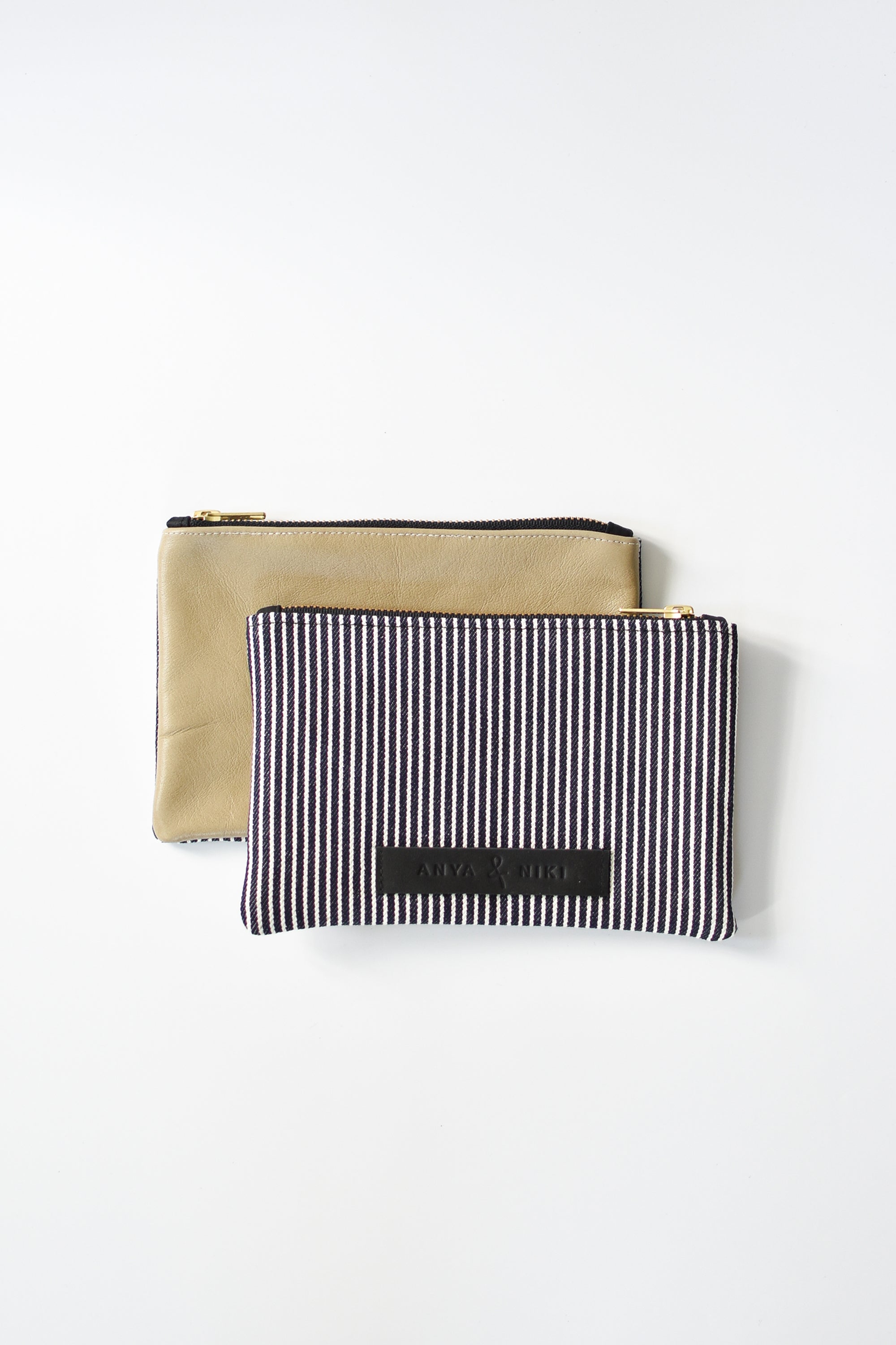 Railroad striped denim and taupe colored leather small pouch with brass zipper and leather logo label.