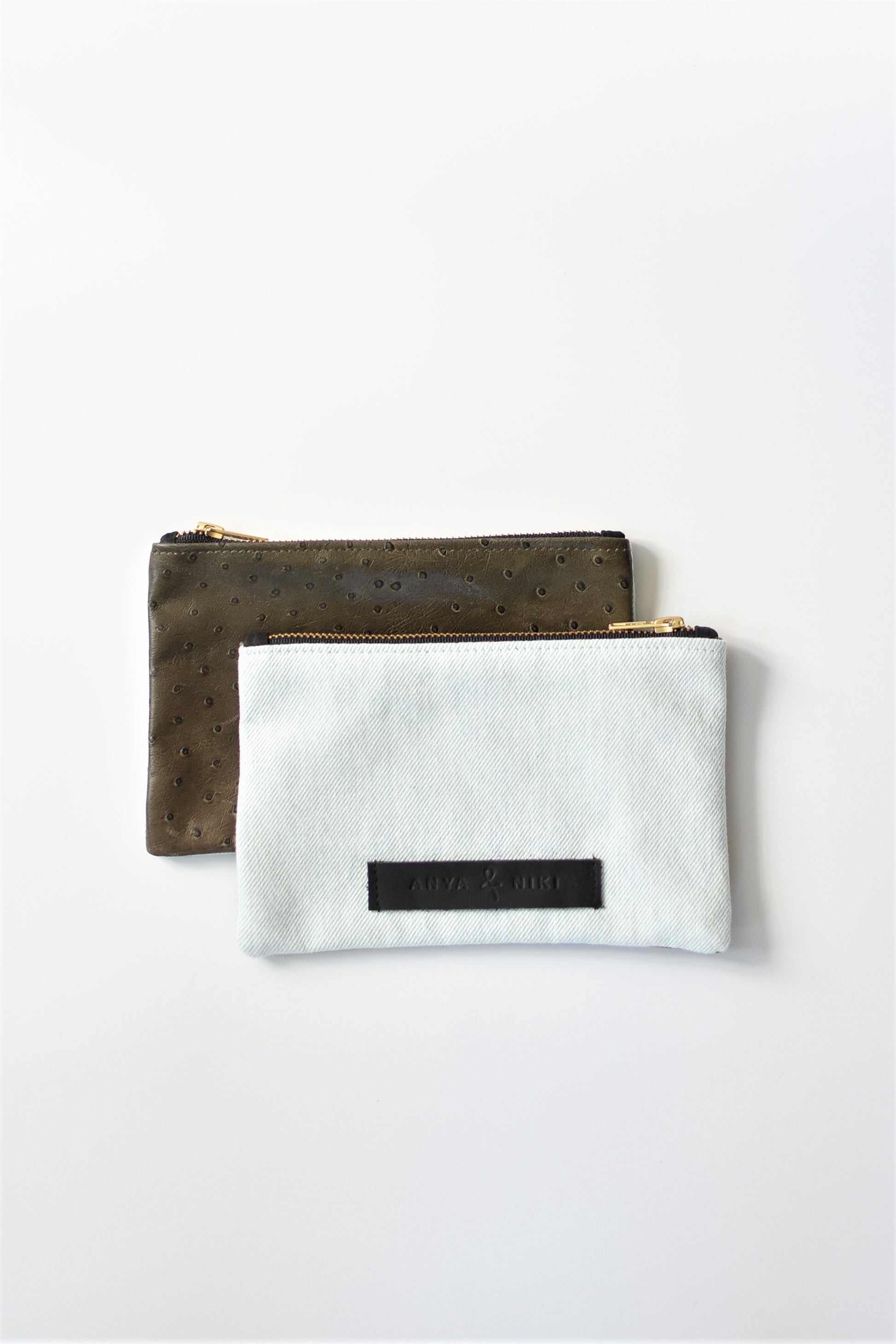 Bleached denim and fern colored embossed leather skin small pouch with brass zipper and leather logo label.