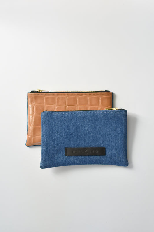 Medium wash denim and caramel colored embossed leather skin small pouch with brass zipper and leather logo label.