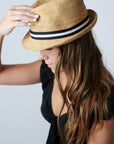 Person wearing natural colored crochet straw fedora hat with black & white stripe band.