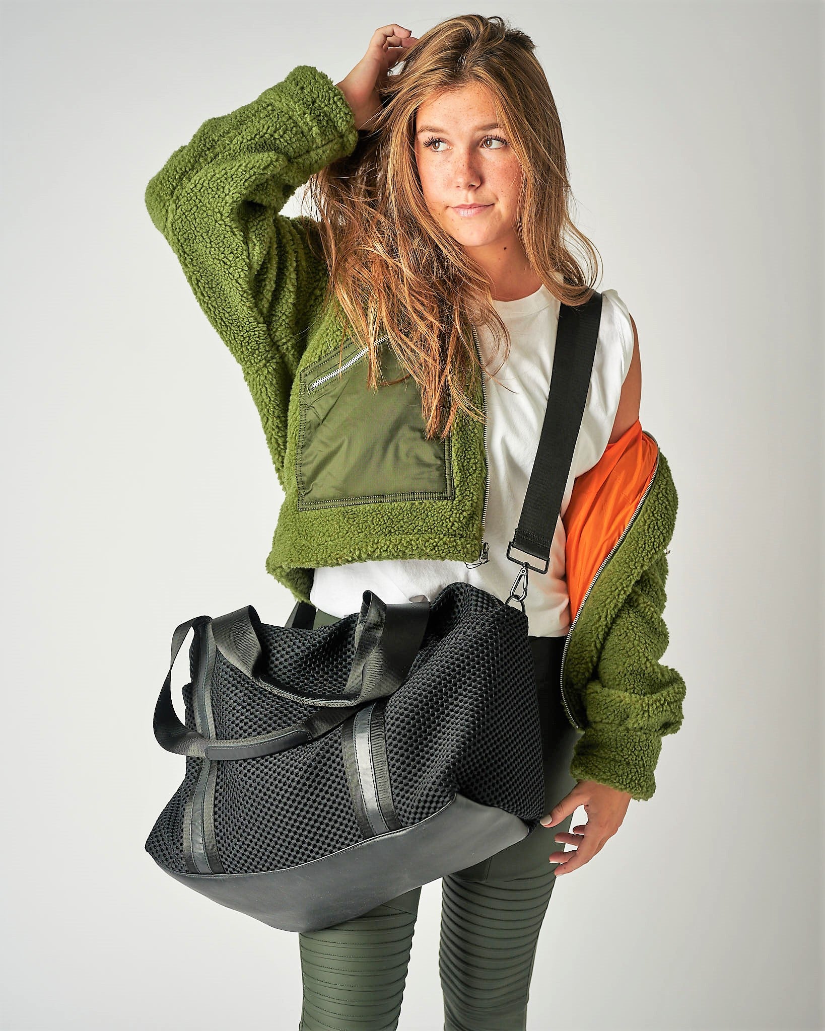 Person wearing the Anya & Niki Stanton Bag - a black mesh duffel bag with leather trim details and black glossy liner.