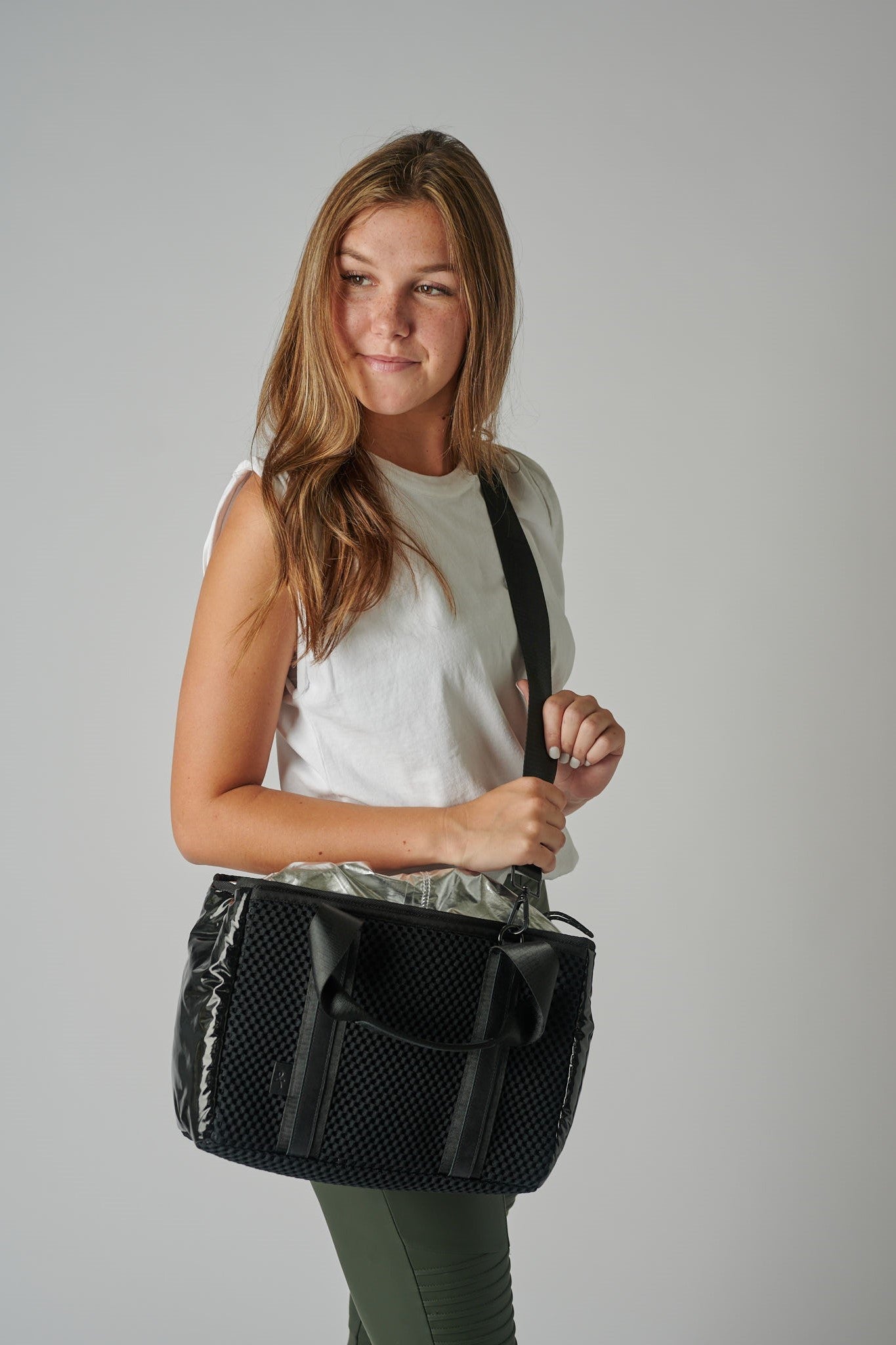 person holding black mesh crossbody tote