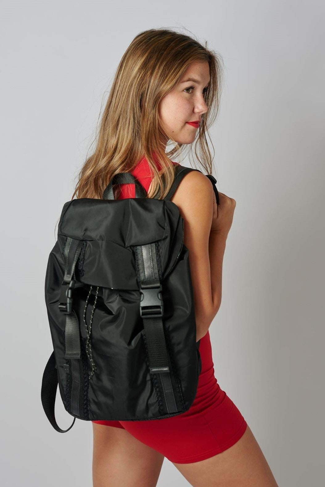 Person wearing the Delray black nylon backpack with mesh back and leather details.