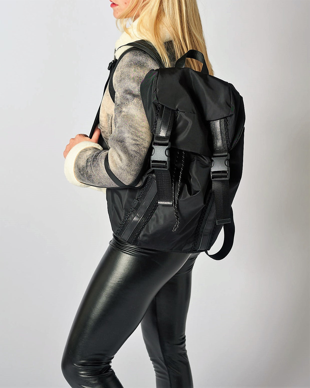 Person wearing the Delray black nylon backpack with mesh back and leather details.