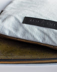 Bleached denim and fern colored embossed leather skin medium pouch with brass zipper and leather logo label.